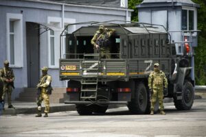 Russian soldiers in uniforms stand next to and in a military truck marked with a Z.