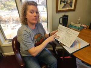 Woman points to paper while sitting at desk