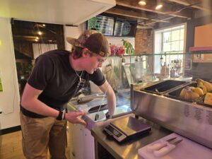 Man scoops acai into bowl behind counter