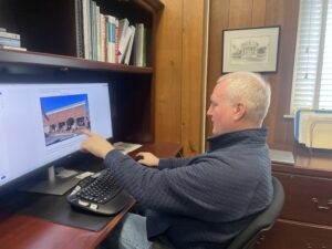 Lexington City Manager Tom Carroll sits at computer desk and points at zoning request.