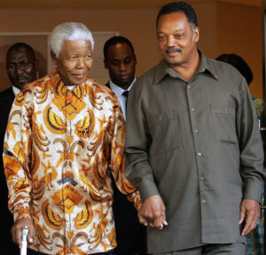Jessie Jackson is holding hands with Nelson Mandela as they walk 