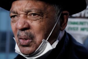 Jackson speaking with a mask underneath his chin.