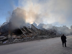 Figure of man next to rumble and smoke. Destroyed buildings due to missile strike.