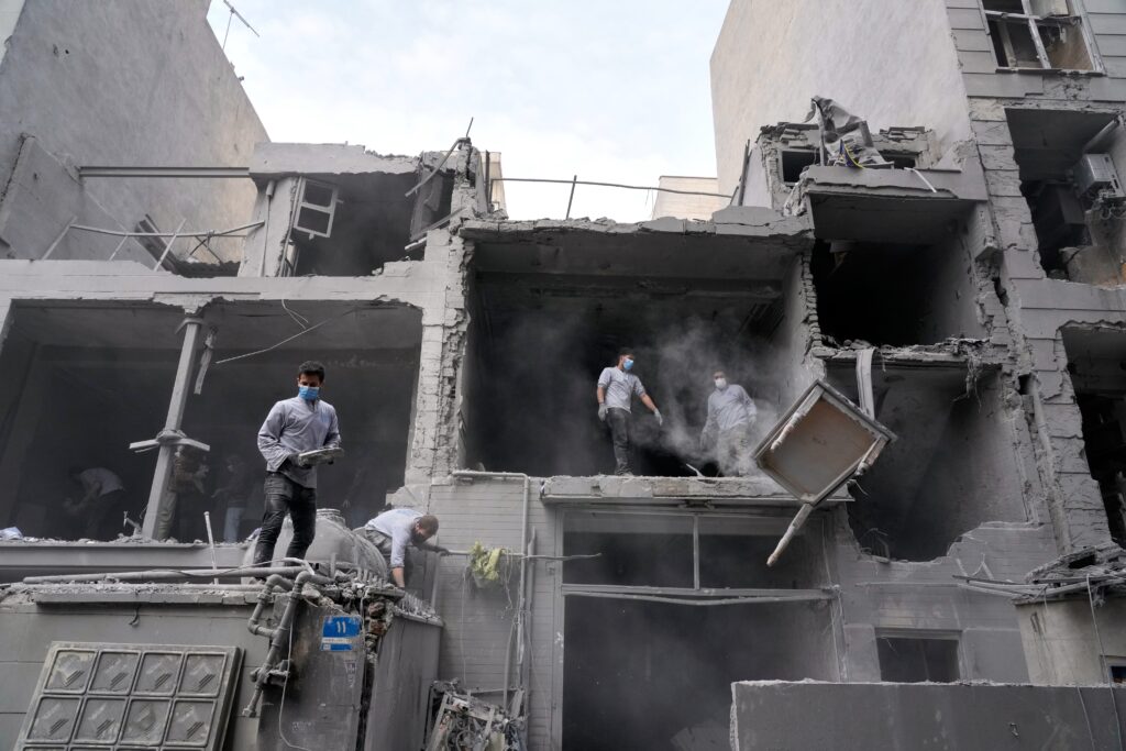 Volunteers clean debris from a residential building damaged when a nearby police station was hit Friday in a U.S.-Israeli strike in Tehran