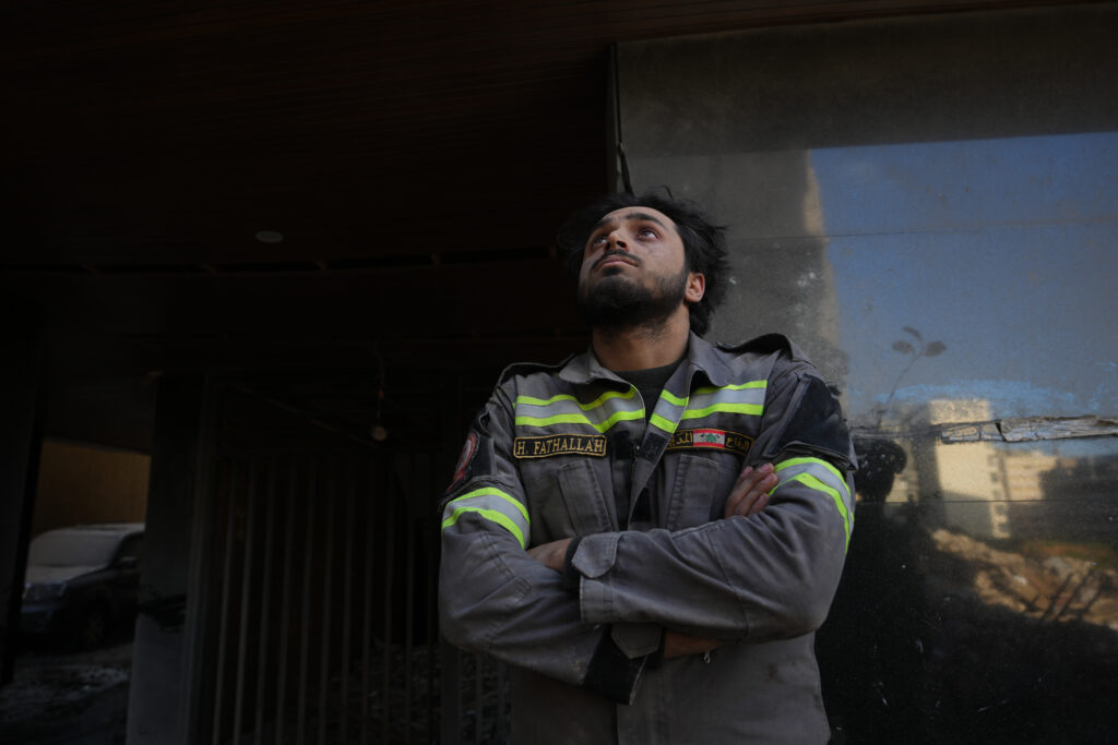 A Lebanese civil defense worker looks upward near the site of a building destroyed in an Israeli airstrike a day earlier in central Beirut, Lebanon. 